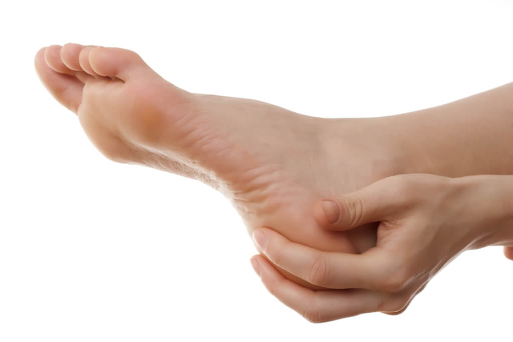 A woman holding their painful heel